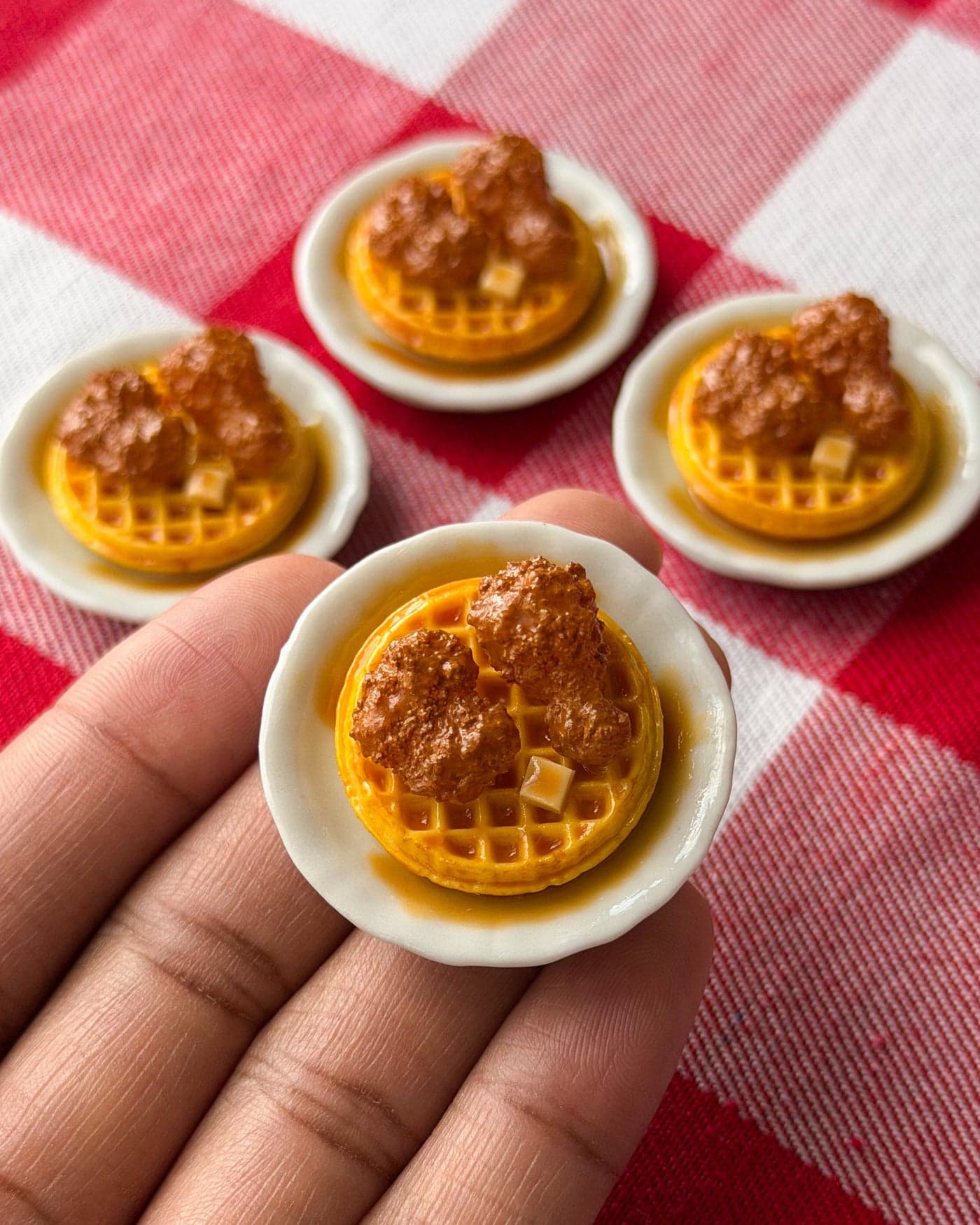 A tiny handcrafted chicken and waffles plate held between Lauryn Terry's fingers
